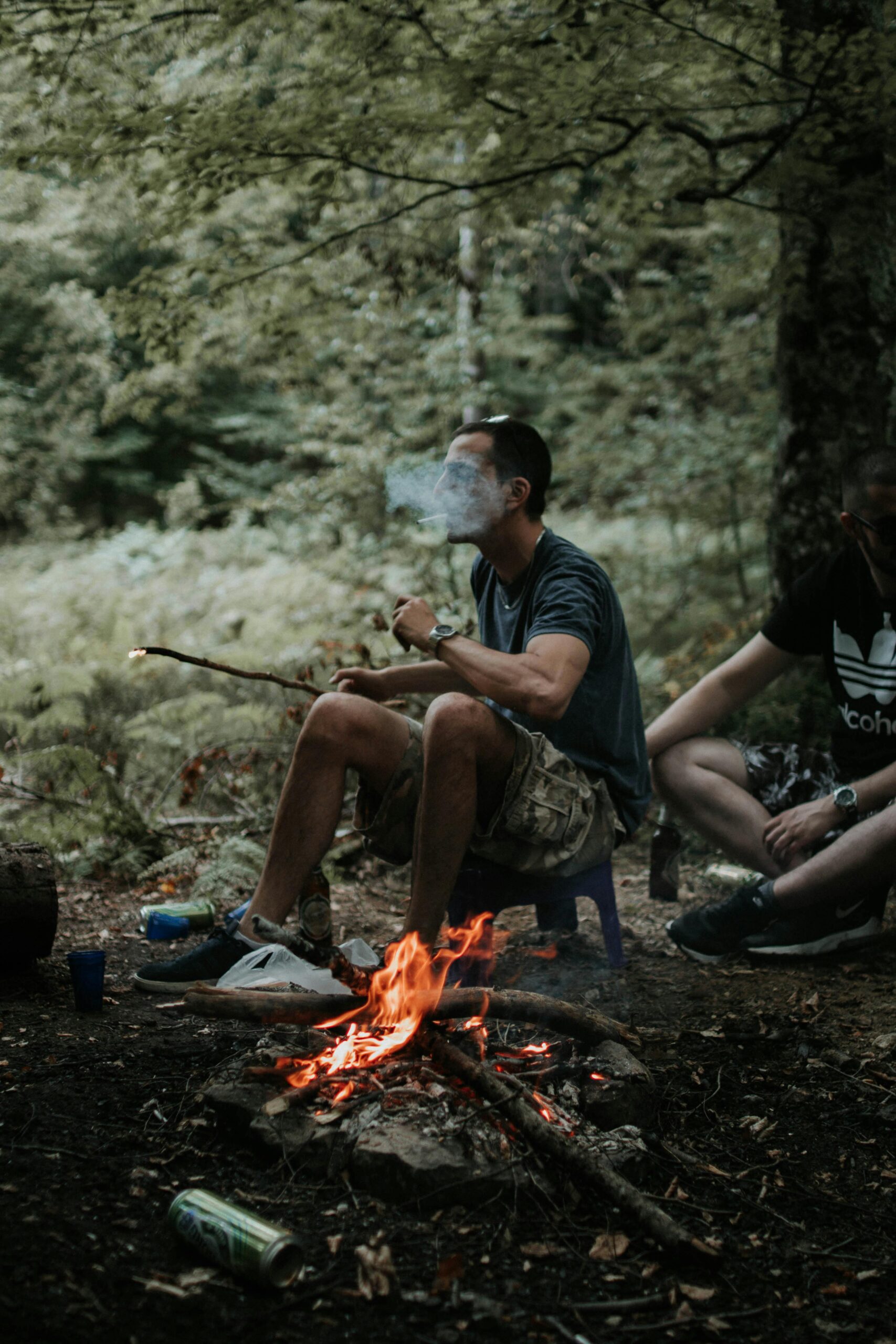Men enjoying a camping trip with a campfire in a lush forest setting.